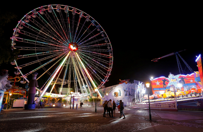 People walk by attractions at the Prater amusement park in Vienna, Austria.